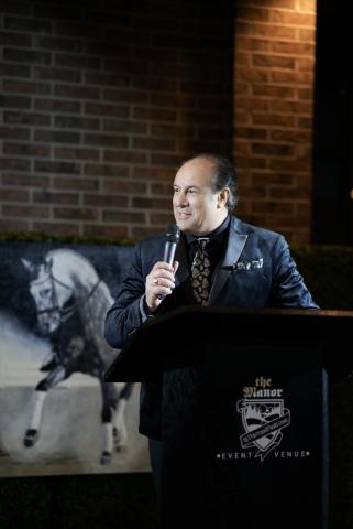 Mayor Steve Pellegrini holding a microphone at a podium, smiling and speaking to crowd