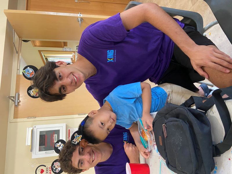 Recreation Staff assisting camper with lunch while sitting at table.